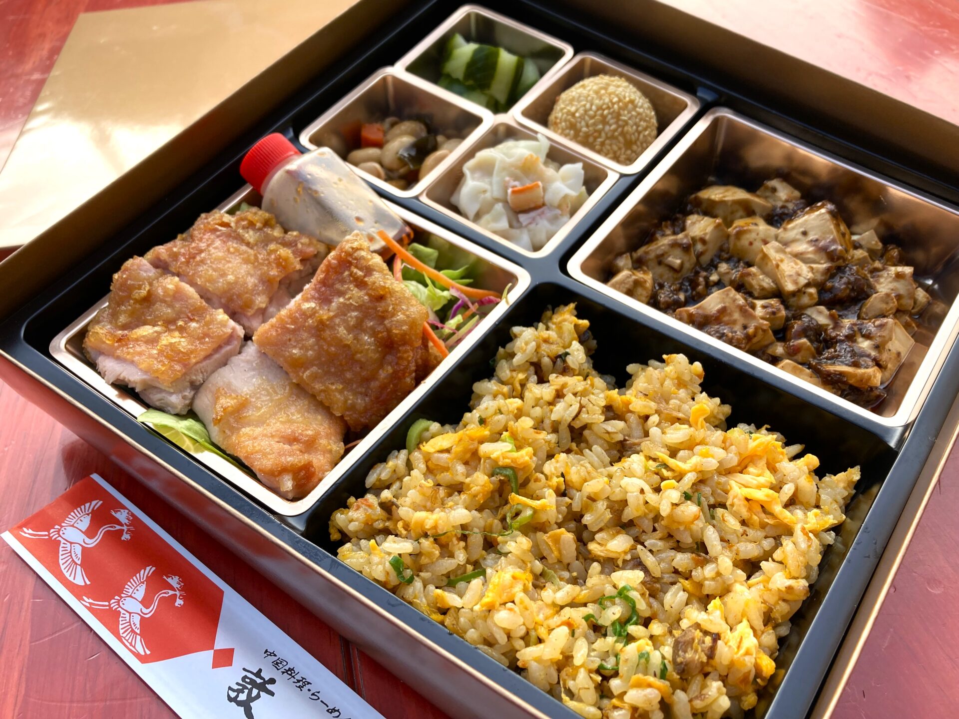 「麻婆豆腐＆ユーリンチ炒飯弁当」2,160円(税込)。カニ焼売や野菜の酢漬け、胡麻団子なども入っている